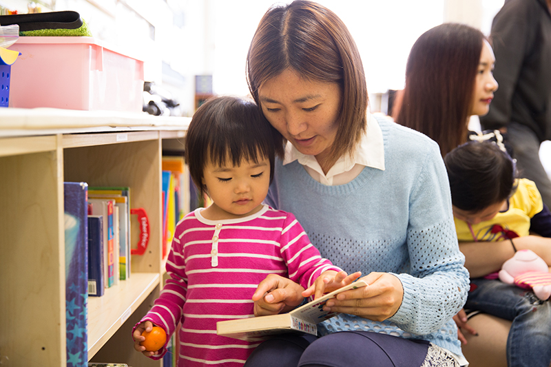 woman reading book to toddler in a child care setting